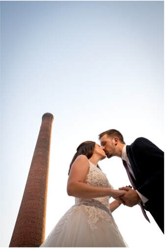 A couple shares a kiss underneath the Judson Mill smokestack