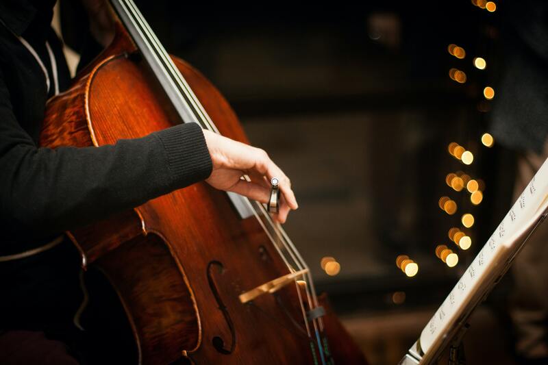 A man plays an upright bass on a stage with lights twinkling in the background