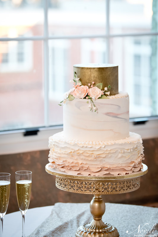 A pink and white wedding cake with a golden topper