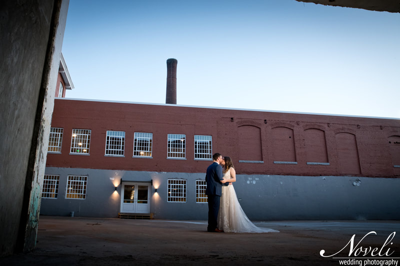 A couple shares a kiss in front of the historic Judson Mill smokestack.