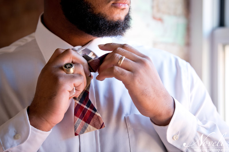 A bearded man in a crisp white shirt adjusts his bow tie.