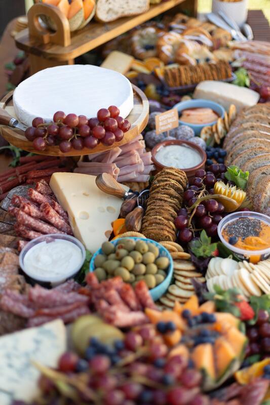 A charcuterie board covered in cheese, crackers, grapes, and meats